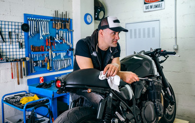 Wall Mural - Mechanic posing with a customized motorcycle in his workshop