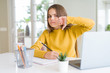 © Krakenimages.com - Beautiful young girl studying using computer laptop and writing on notebook with angry face, negative sign showing dislike with thumbs down, rejection concept