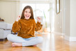 © Krakenimages.com - Beautiful young girl kid sitting on the floor at home celebrating surprised and amazed for success with arms raised and open eyes. Winner concept.