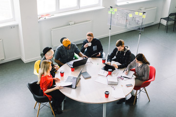 Wall Mural - Top view of multiracial young creative people in modern office. Group of young business people are working together with laptop, tablet, smart phone, notebook. Successful hipster team in coworking.