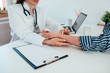 © bnenin - Close-up image of female doctor checking male patient's pulse while sitting at the desk at medical office.