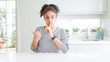 © Krakenimages.com - Beautiful african american woman with afro hair wearing casual striped sweater asking to be quiet with finger on lips pointing with hand to the side. Silence and secret concept.