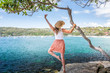 Happy woman dance pirouette beside tree by the ocean