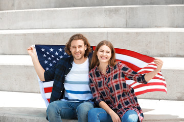 Wall Mural - Happy young couple with USA flag outdoors. Independence Day celebration