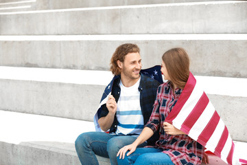 Wall Mural - Happy young couple with USA flag outdoors. Independence Day celebration