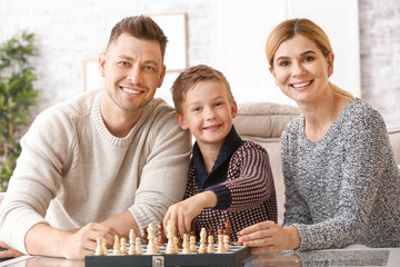 Wall Mural - Happy couple with little adopted children playing chess at home