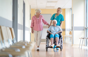 Wall Mural - Elderly woman on wheelchair with her daughter and nurse