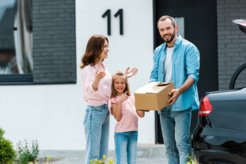 Wall Mural - cheerful and cute kid pointing with finger at father with box