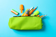Pencil case with school supplies on blue background, space for text