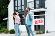© LIGHTFIELD STUDIOS - happy man and woman celebrating near house and board with sold letters