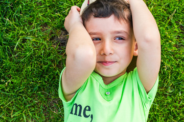 Wall Mural - cheerful smiling boy lying on the grass in the summer