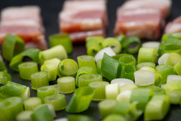 Wall Mural - Uncured Apple Smoked Bacon garnished with Green Onion Scallions. Black natural stone background.