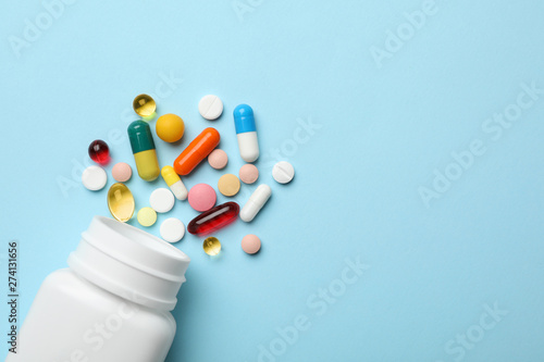 Fotomural Bottle and scattered pills on color background, top view