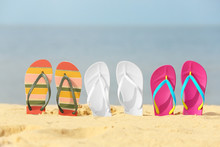 Different Bright Flip Flops In Sand. Beach Accessories