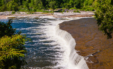 Wide Flat Waterfall Flowing Into River.