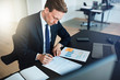 © Flamingo Images - Businessman signing papers while going over documents in an offi