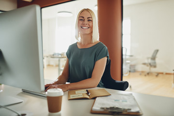 Wall Mural - Young businesswoman smiling while working at her office desk