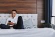 © Yakobchuk Olena - Cheerful man with smartphone is drinking coffee in bedroom