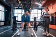 © Viacheslav Yakobchuk - Dark-haired trainer lifting barbell showing it to his client