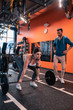© Viacheslav Yakobchuk - Plump strong woman lifting barbell standing near trainer