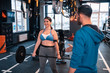 © Viacheslav Yakobchuk - Woman smiling after lifting barbell standing near trainer