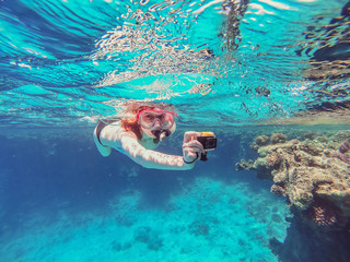 Snorkeling Girl with an action camera floats in the sea and shoots a video camera