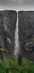 Fotomurales - high waterfall plummets off a rock and grass cliff in the Swiss Alps