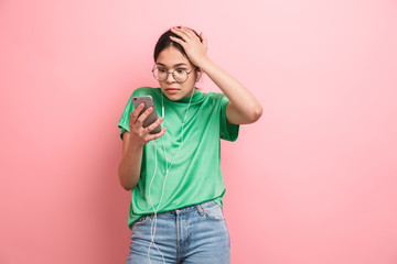 Canvas Print - Photo of shocked young girl wearing round eyeglasses using earphones while holding smartphone