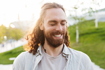 Handsome cheerful young bearded man walking outdoors