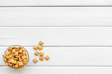 Puffins, corn cereals in bowls on white wooden background top view space for text