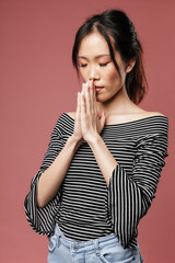 Photo closeup of concentrated asian woman dressed in basic wear keeping palms together and praying with closed eyes