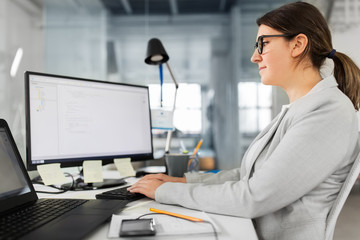 business, technology and people concept - businesswoman in glasses with computer working at office