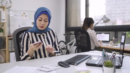 Wall Mural - islam female leader with scarf religion pick up phone call on cellphone typing on computer talking with customer. japanese employee coworker helping manager record down writing on notebook teamwork