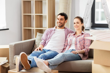 Wall Mural - moving, people, repair and real estate concept - happy couple with cardboard boxes sitting on sofa at new home