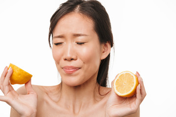 Sticker - Confused beautiful asian woman posing isolated over white wall background eat lemon citrus.