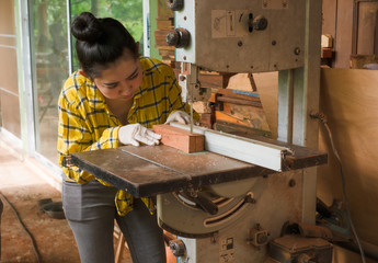 Women standing is craft working cut wood at a work bench with band saws power tools at carpenter machine in the workshop