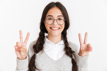 Wall Mural - Photo closeup of cheerful teenage girl wearing eyeglasses and school uniform smiling while showing peace sign with fingers