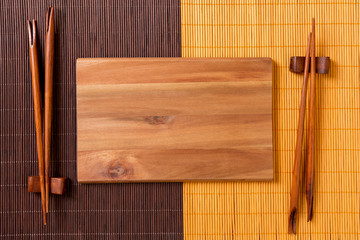 Wall Mural - Empty rectangular wooden plate with chopsticks for sushi and soy sauce on wood background. Top view with copy space