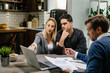 © Drazen - Young couple communicating with real estate agent while using laptop on a meeting.