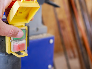 Wall Mural - Carpenter starting the planing machine in a small workshop, shallow depth of field, copy space