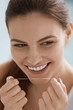 © puhhha - Dental floss. Smiling woman cleaning white teeth with floss