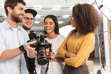 Wall Mural - Portrait of attractive multiethnic people looking at professional camera during fashion photo shooting in studio