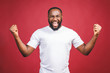 © denis_vermenko - I'm winner. Portrait of happy african american man isolated over red background.