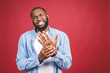 © denis_vermenko - Young african american man  suffering pain on hands and fingers, arthritis inflammation. Isolated over red.