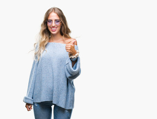 Beautiful young blonde woman wearing sunglasses over isolated background doing happy thumbs up gesture with hand. Approving expression looking at the camera with showing success.