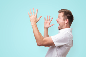 Sticker - Young man screaming aside with hands gesture isolated on blue background