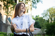 © Богдан Маліцький - student standing near the university, holding papers in her hands and smiling against the background of the college, she goes to school
