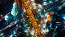 Beautiful Top View Time-lapse Of Car Traffic At Roundabout Lane And Buildings. 4K Drone Aerial Zoom Out. Urban Cityscape Concept Or Abstract Of Advanced Innovation, Financial Technology, Energy Power