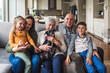 © Cavan Images - Portrait of multigenerational family sitting on living room couch