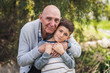 © Cavan Images - Close up portrait of grandfather and grandson hugging outside